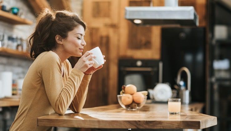 Giovane assapora il caffè in cucina