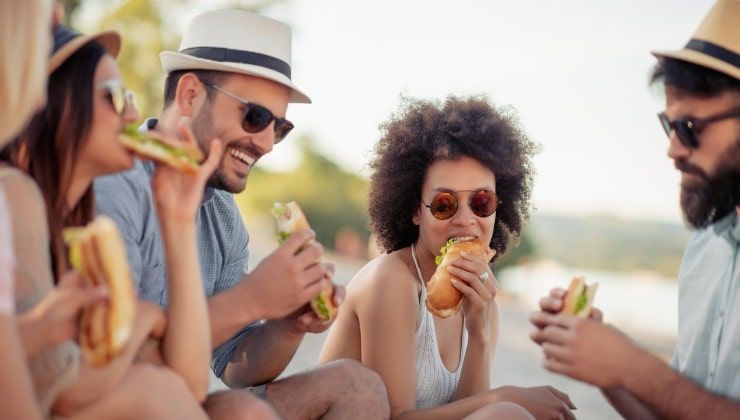 Amici mangiano panino al mare